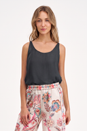 A woman modeling a sleeveless dark charcoal scoop-neck top paired with high-waisted floral print pants against a clean white studio background.